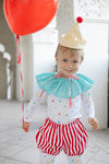 Child in clown costume with red balloon indoors