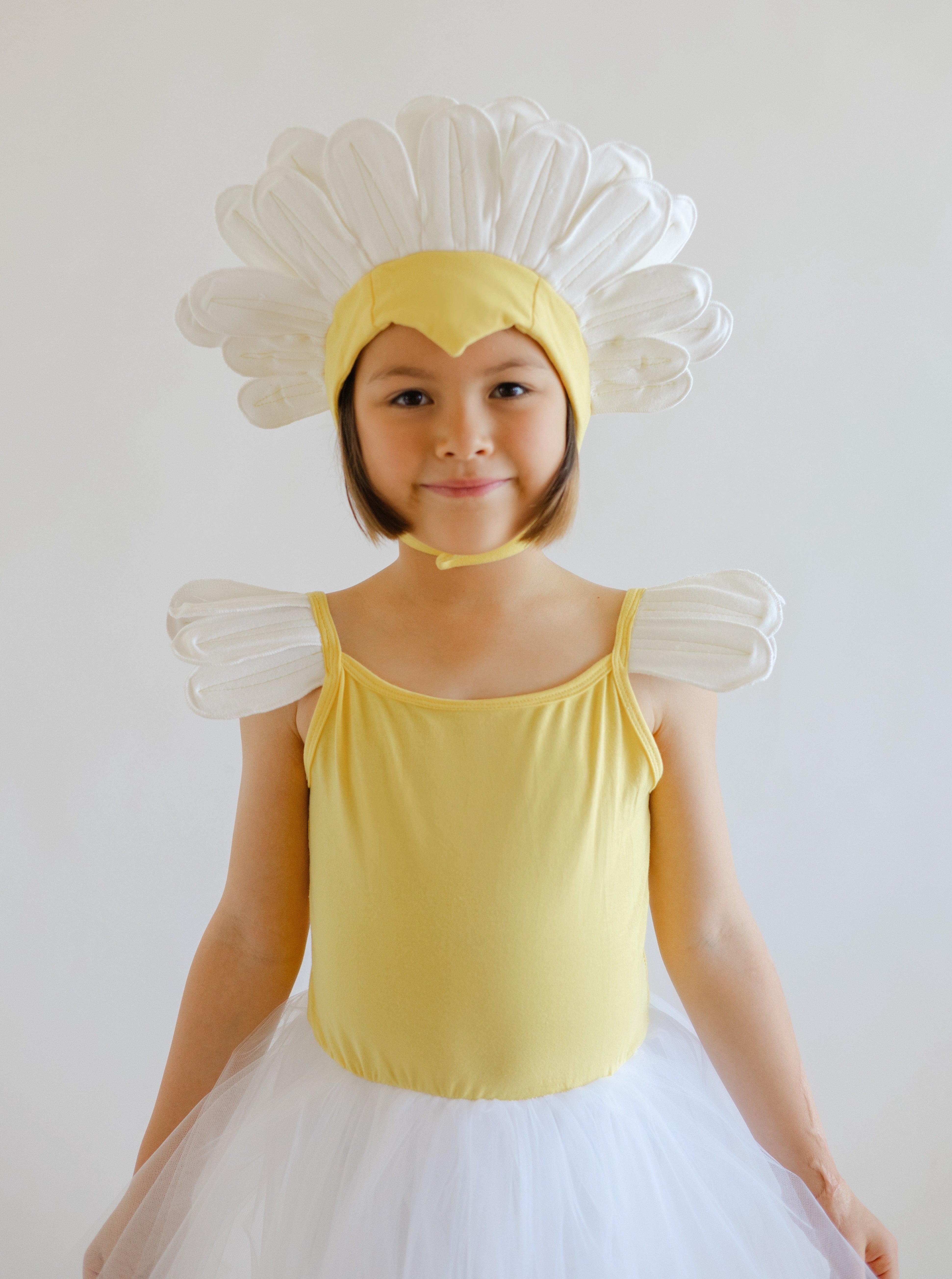 Child wearing a yellow dress and flower costume against a white background