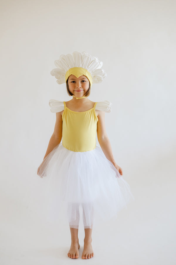 Child in a yellow dress with flower headband and white skirt on a plain background