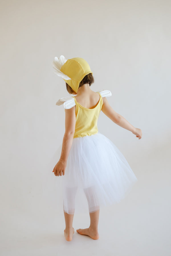 Child wearing a yellow dress with white wings and a yellow hat on a plain background