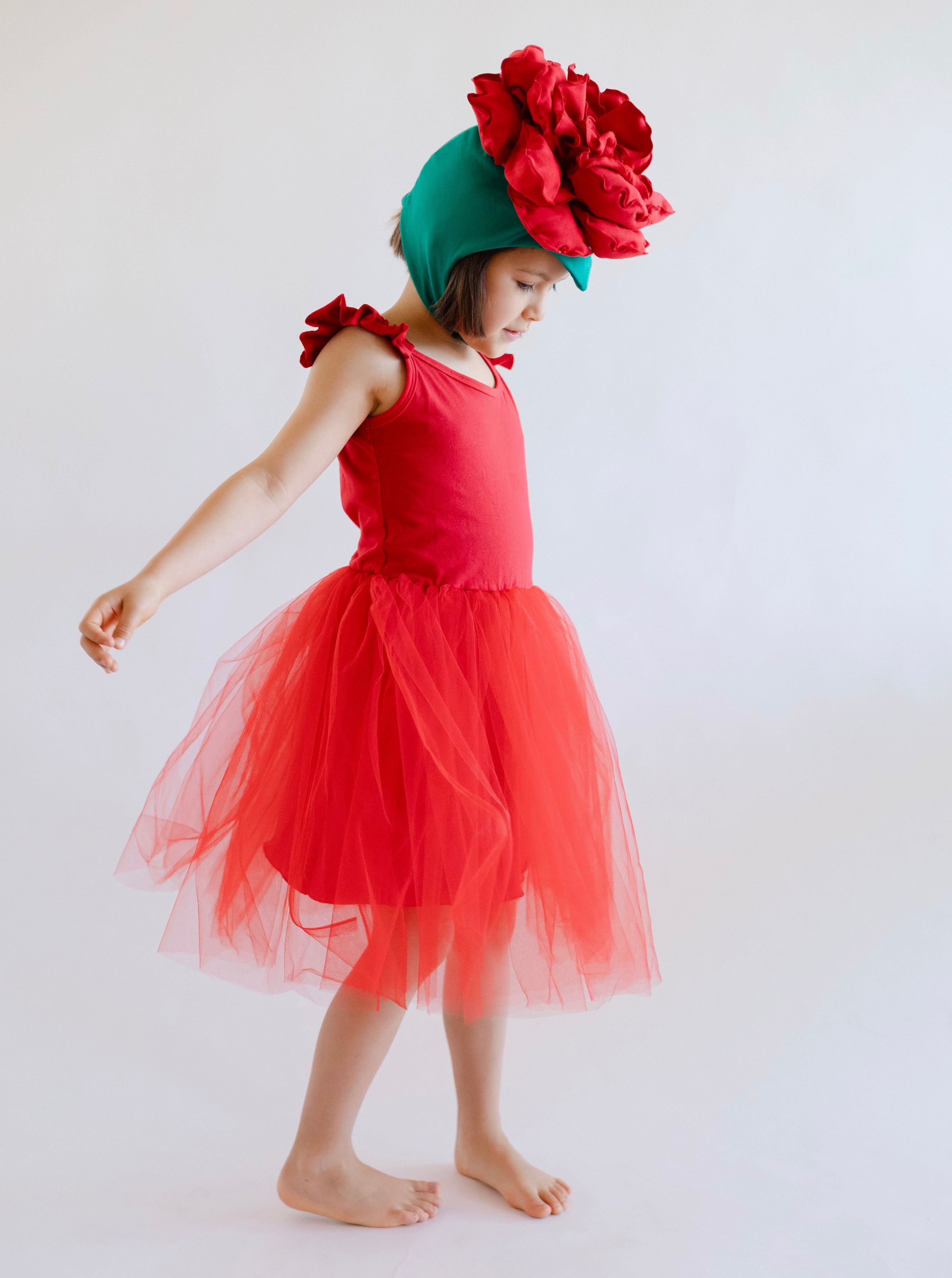 Child wearing a red dress with a large flower headband on a white background