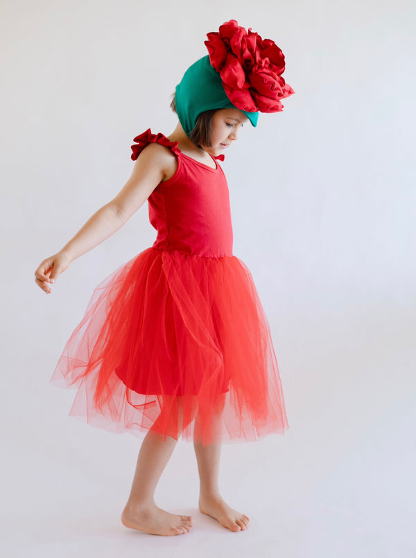 Child wearing a red dress with a large flower headband on a white background