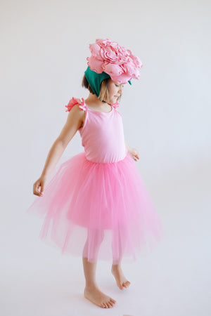 Child wearing a pink peony flower fairy costume with hand-sewn peony hat and ruffle tutu dress on white background