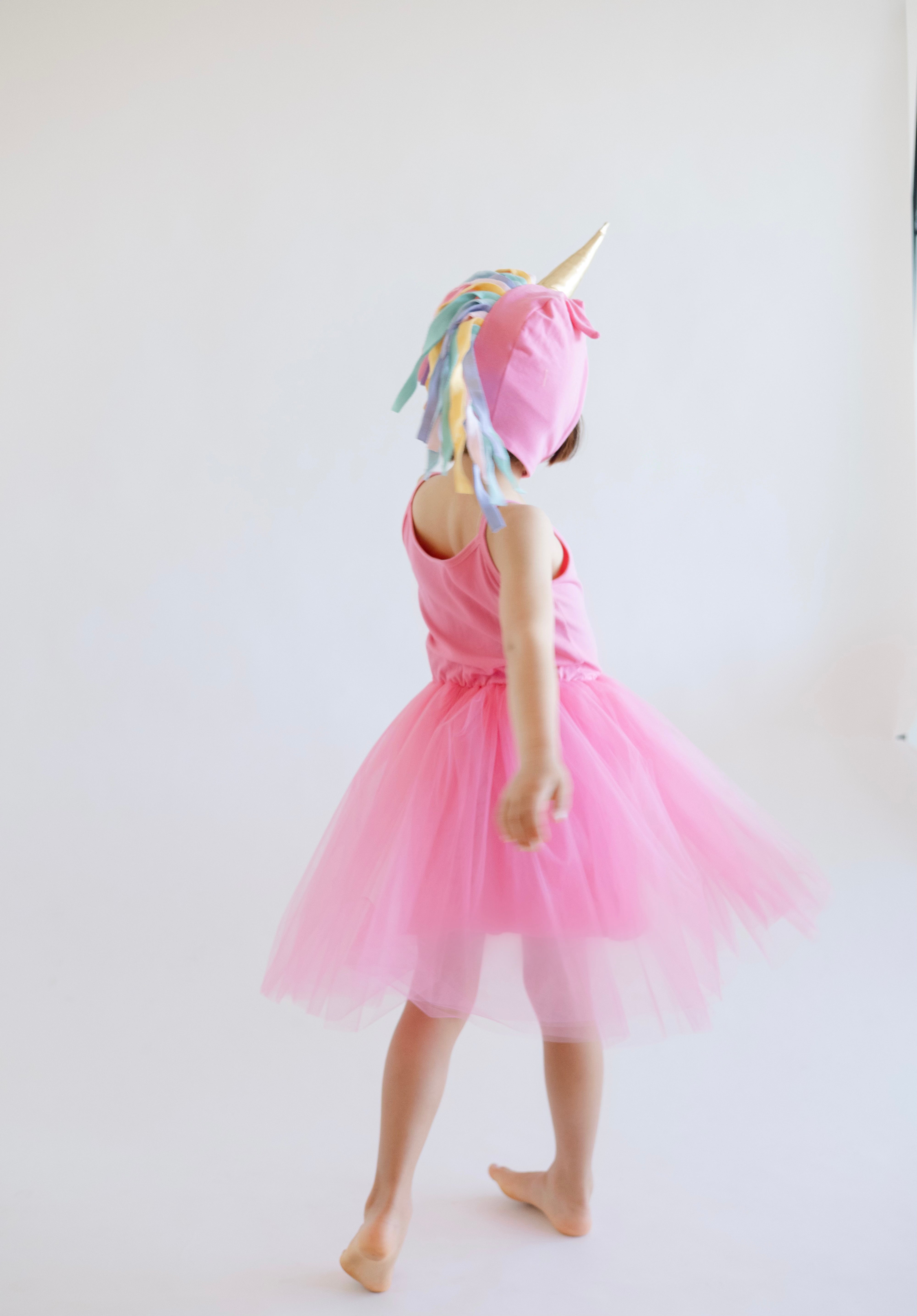 Person wearing a pink unicorn costume with a white background