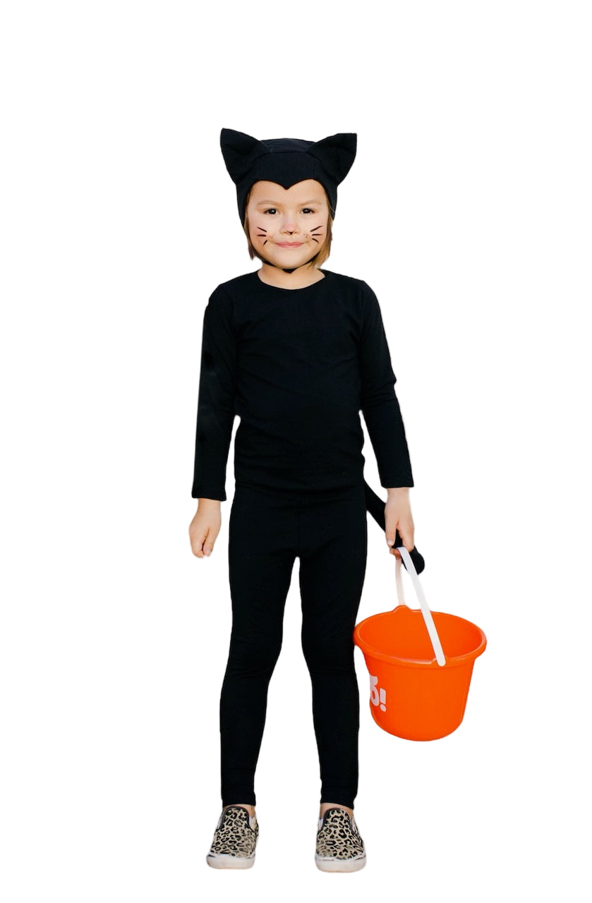 Child in a black cat costume holding an orange bucket on a white background