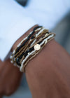 Set of 12 Fair Anita elastic bracelets with Burst charm, stacked on a wrist