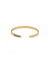 Gold bracelet with 'feminist' engraving on a white background