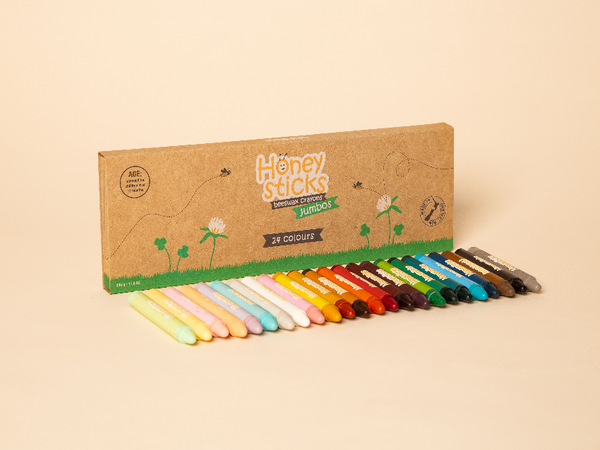 Set of colorful Honey Sticks crayons with a cardboard box on a beige background. Upgrade your child's art set with Honeysticks Jumbo 24-Pack. Handmade in New Zealand from 100% pure beeswax and food-grade pigments. These non-toxic, paraffin-free crayons are perfectly sized for children with a developing pencil grasp. The ultimate safe and sustainable gift for creative kids!