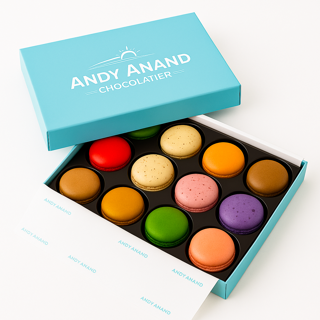 Box of colorful macarons with Andy Anand Chocolatier branding on a white background