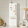 Tiny Land white wooden play kitchen fridge with gold handles styled in a child's bedroom with a teddy bear and wicker basket