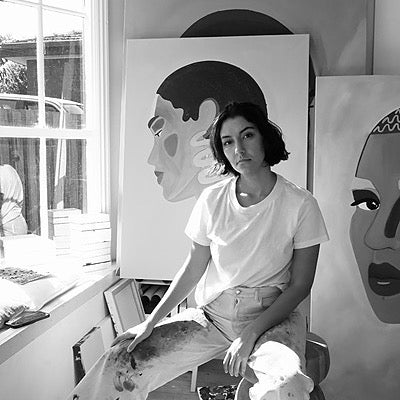 Woman sitting in front of artwork in a studio setting