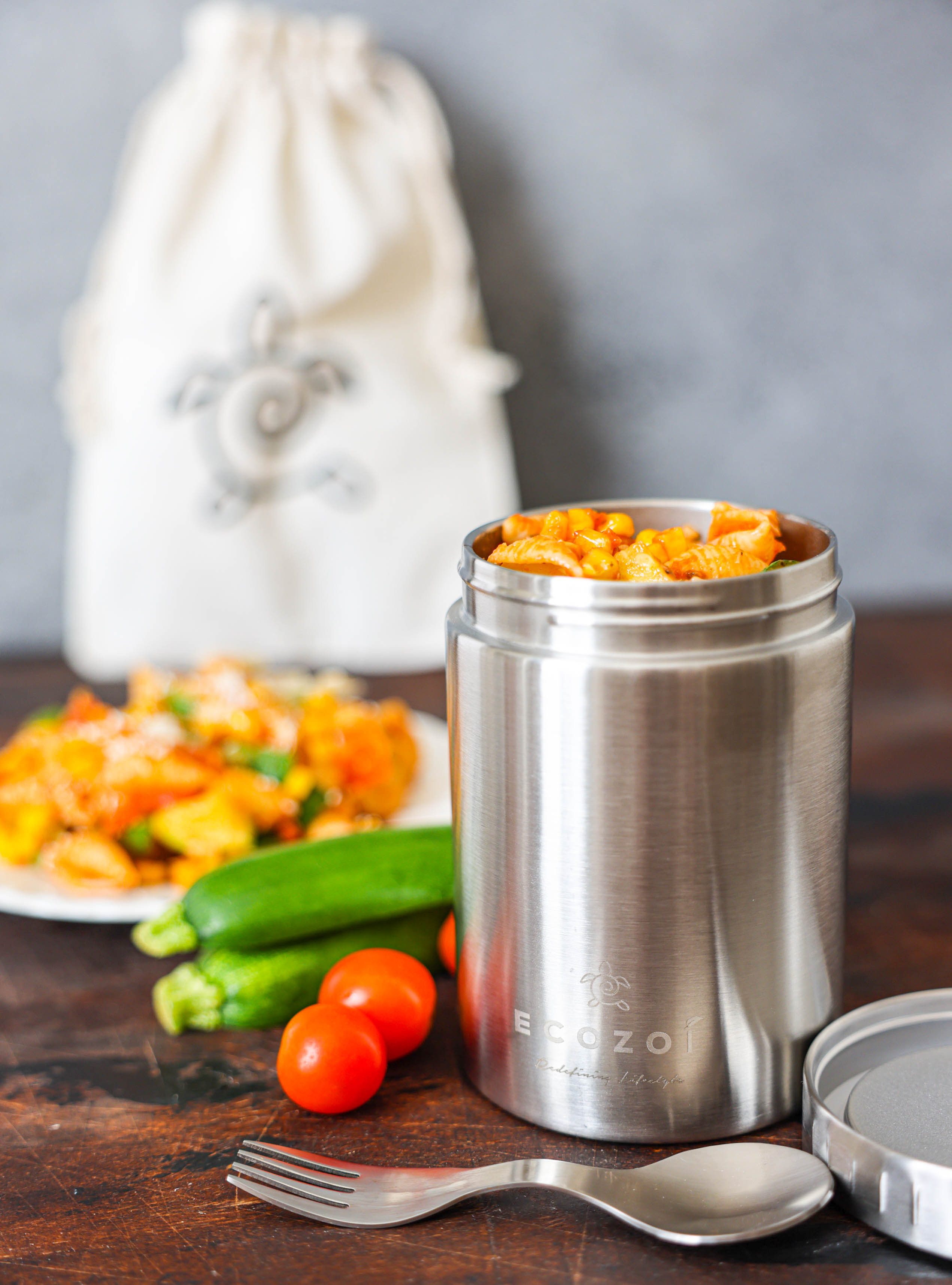 Stainless steel food container with food on a wooden table, with a blurred background