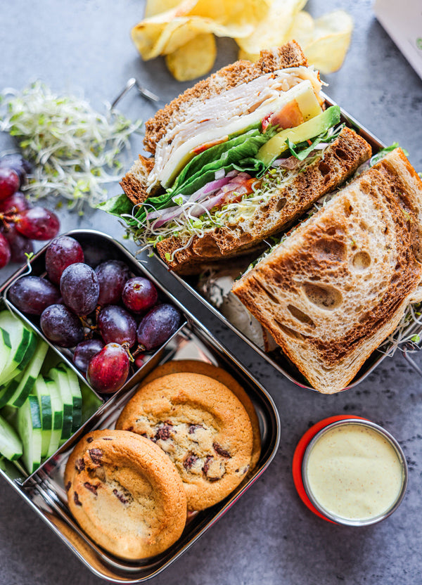Ecozoi leak-proof stainless steel lunch box open showing 3-compartment top tier and bottom tier with food