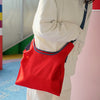 Person carrying the HowBottle Little Snake limited edition red bag outdoors against a colourful wall