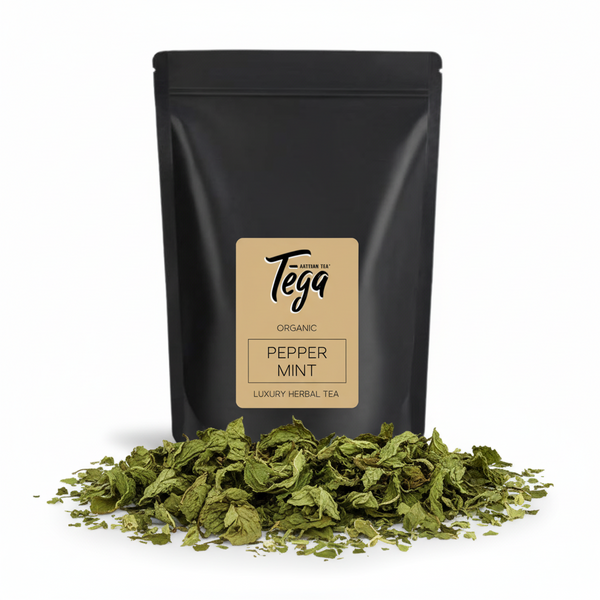 Black tea packaging with Tega label and peppermint leaves on a white background