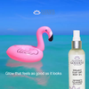 Glimmer Goddess organic silky dry body oil bottle with pink flamingo floatie against a blue ocean background