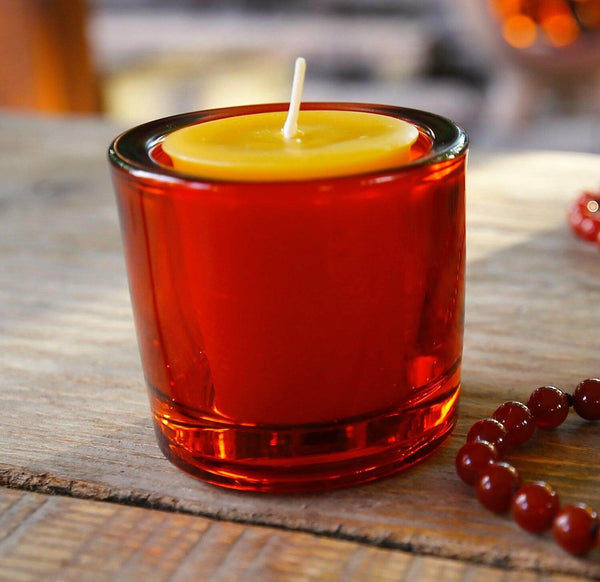 Candle in a glass container with a wooden background