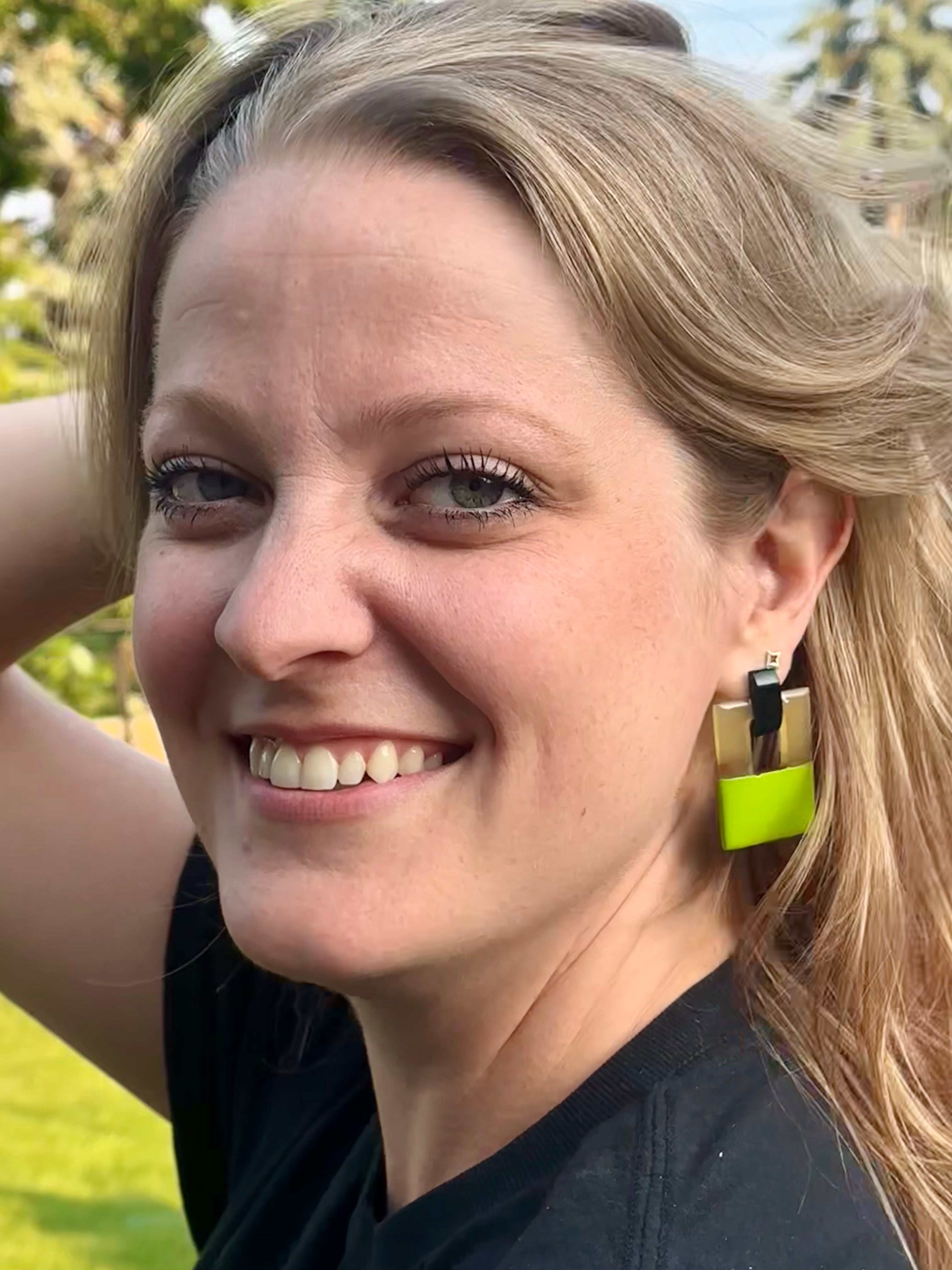 Woman with blonde hair and green earrings outdoors