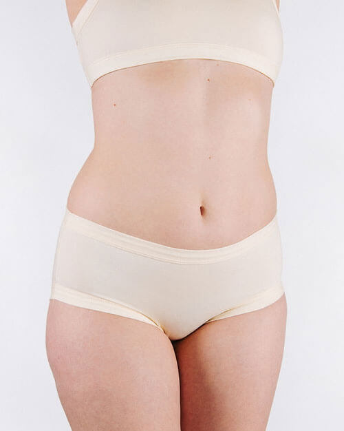 Person wearing a beige bra and panties set on a light gray background
