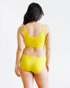 Side view of model wearing Thunderpants Star Fruit Hipster underwear in yellow chartreuse