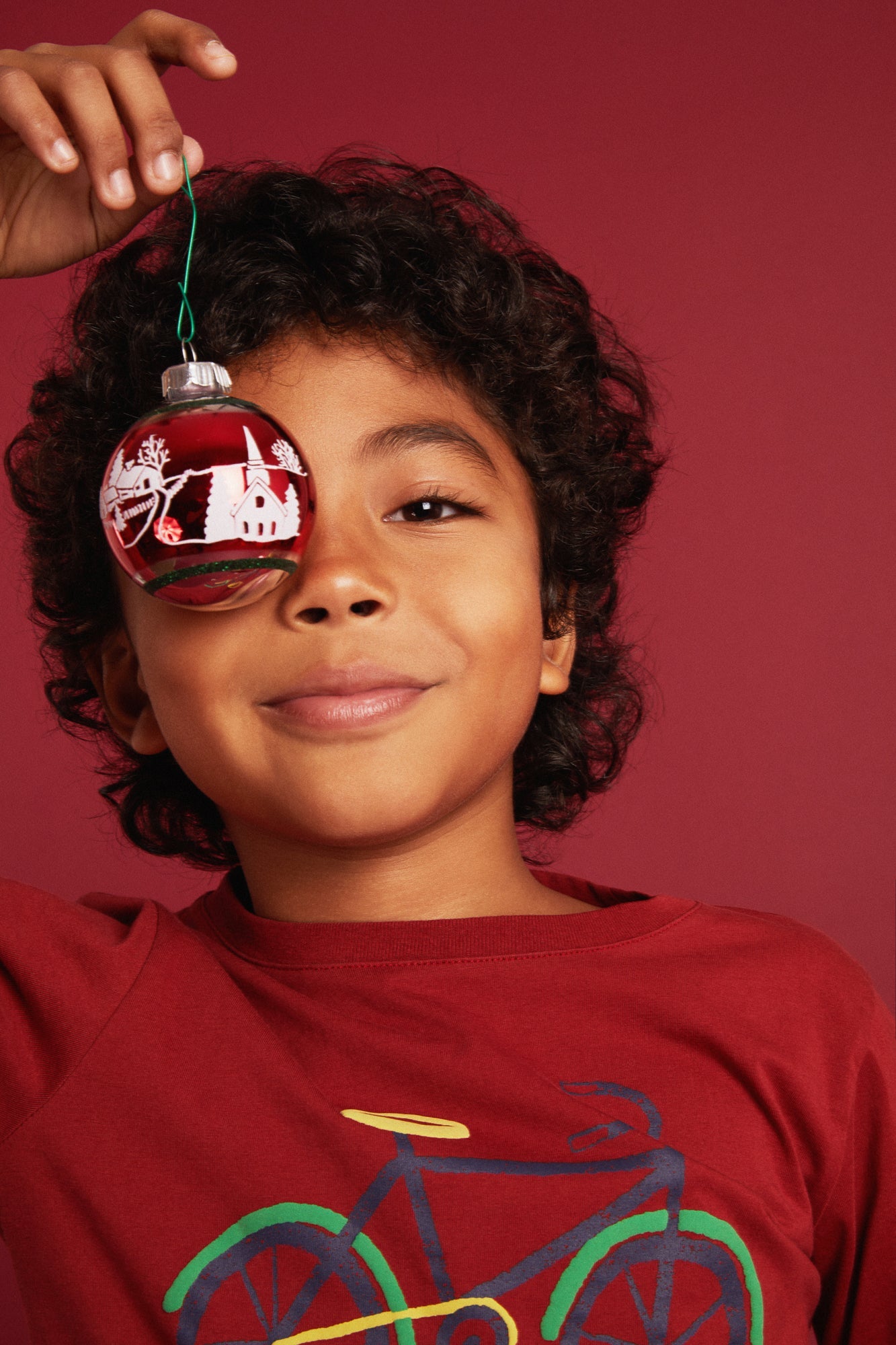 Close-up lifestyle shot of Mon Coeur kids recycled cotton bicycle print t-shirt in Cardinal Red
