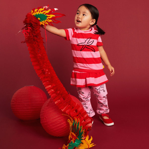 Child playing with a red dragon toy against a red background
