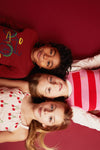 Child modelling Mon Coeur Bicyclette long-sleeve tee in Cardinal Red, casual outdoor setting