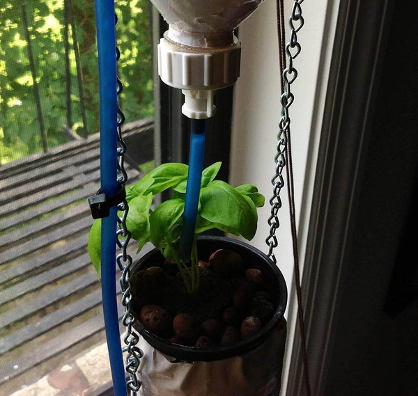 Potted plant hanging from a blue stand with a water source above it, on a balcony.