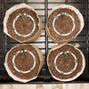 Four seedling pots with soil and small plants on a metal tray.