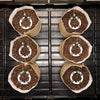 Six coffee filter planters with soil and decorative elements on a metal surface