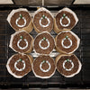 Nine round brown seed starting pots with white labels on a black tray.