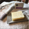 Bar of soap on a soap dish with a branded soap bar in the background.