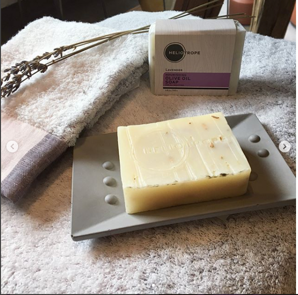 Bar of soap on a soap dish with a branded soap bar in the background.