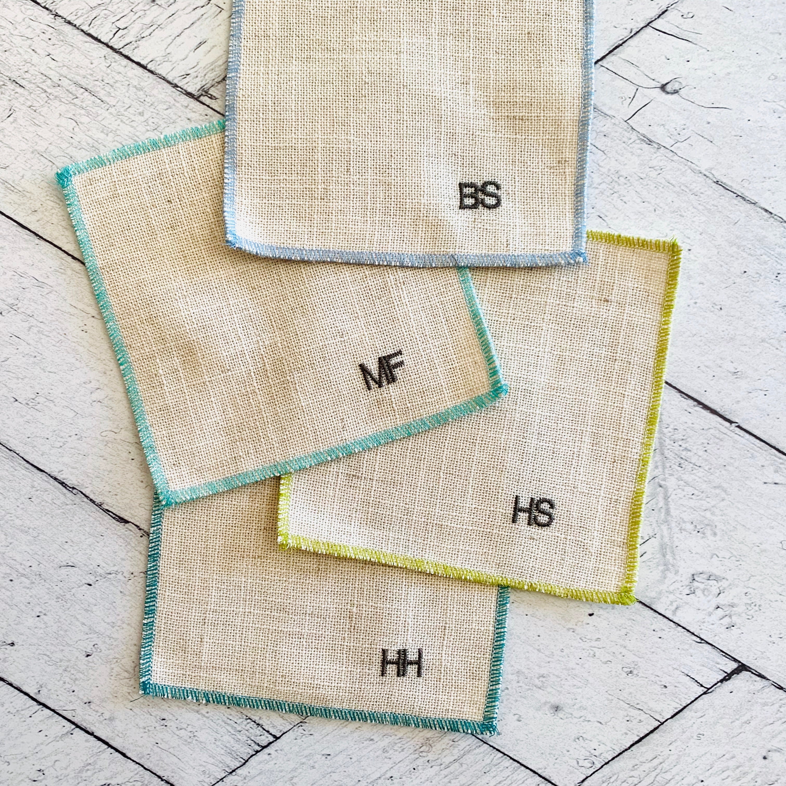 Close-up of sweary cocktail coasters handmade by Dot and Army, showing embroidered letter detail on linen fabric