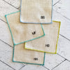 Close-up of sweary cocktail coasters handmade by Dot and Army, showing embroidered letter detail on linen fabric