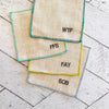 Sweary cocktail coasters styled on a bar cart with drinks, showing the full set of 8 funny linen coasters