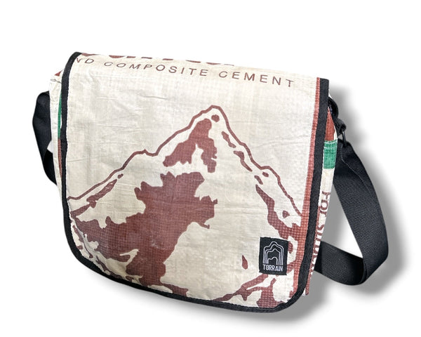 Messenger bag with mountain design and 'Composite Cement' branding on a white background