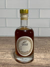 Bottle of homemade vanilla extract on a wooden surface with a tiled wall background