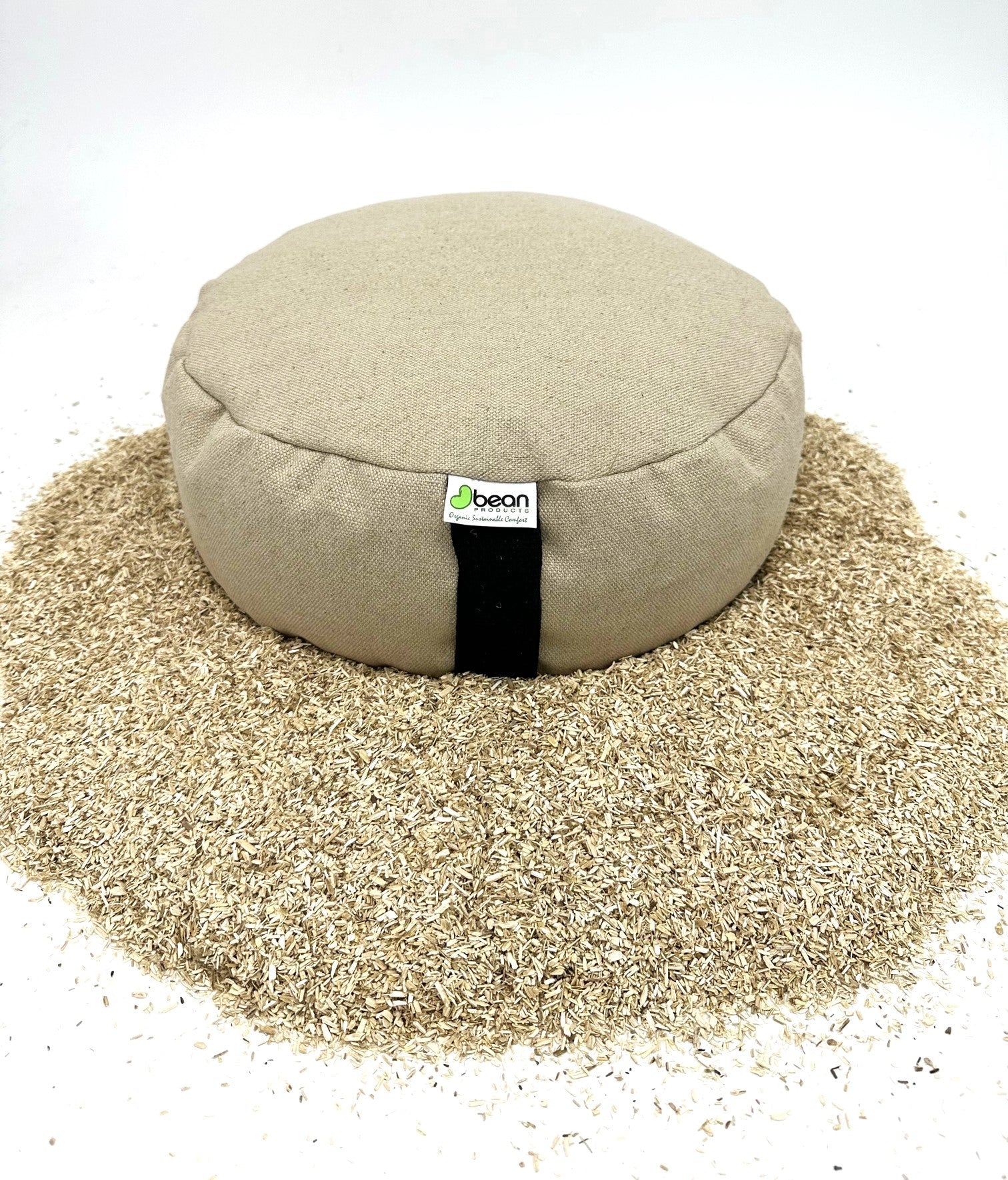 Round meditation pillow with a visible brand label on a bed of sand.