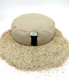 Round meditation pillow with a visible brand label on a bed of sand.
