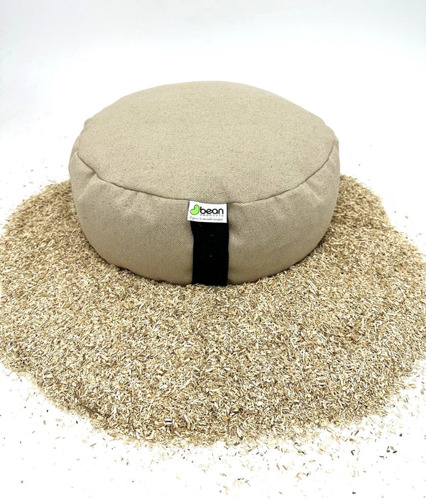 Round meditation pillow with a visible brand label on a bed of sand.