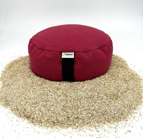 Red bean bag cushion on a bed of beans with a visible brand label.
