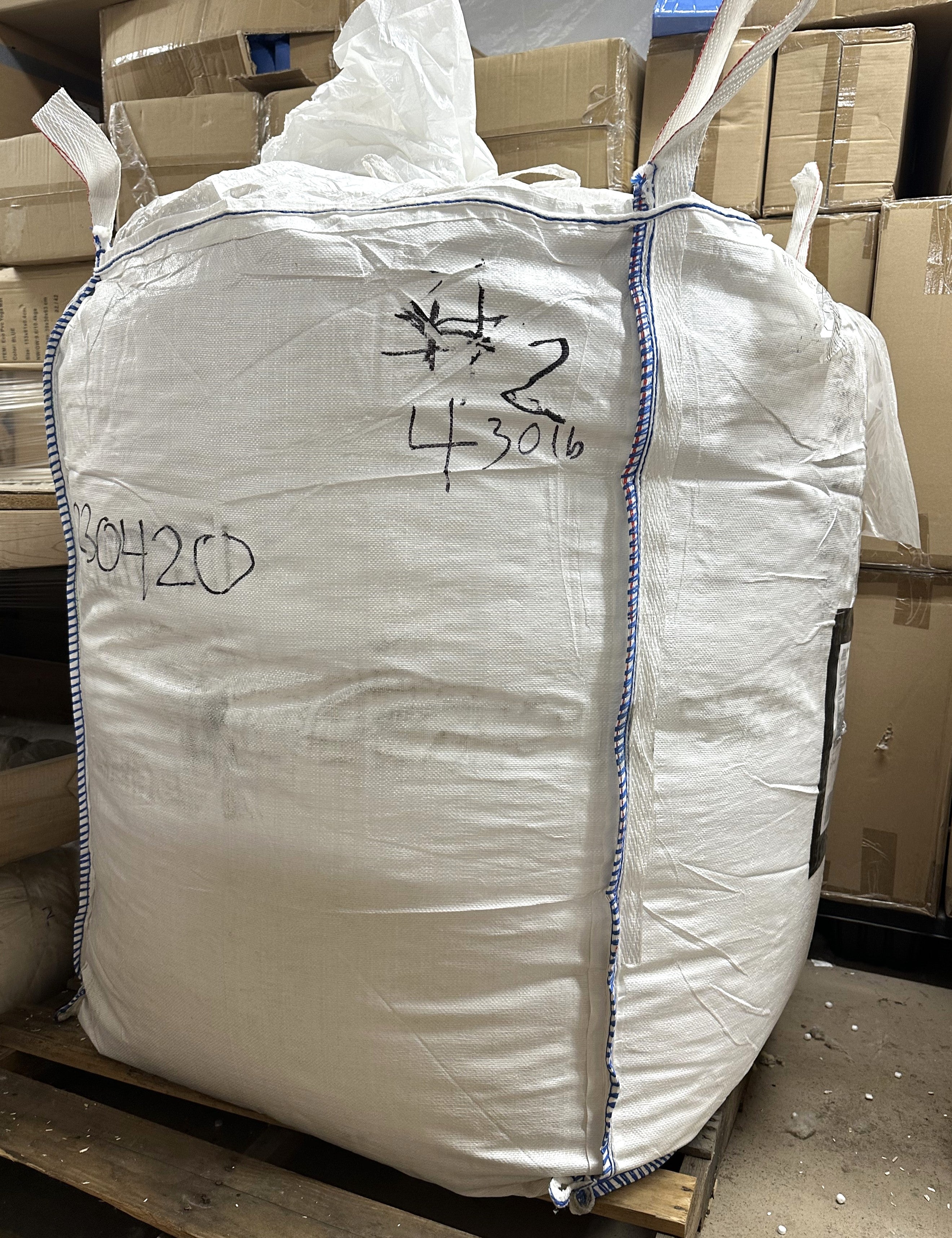 Large white编织袋 in a warehouse setting with boxes in the background