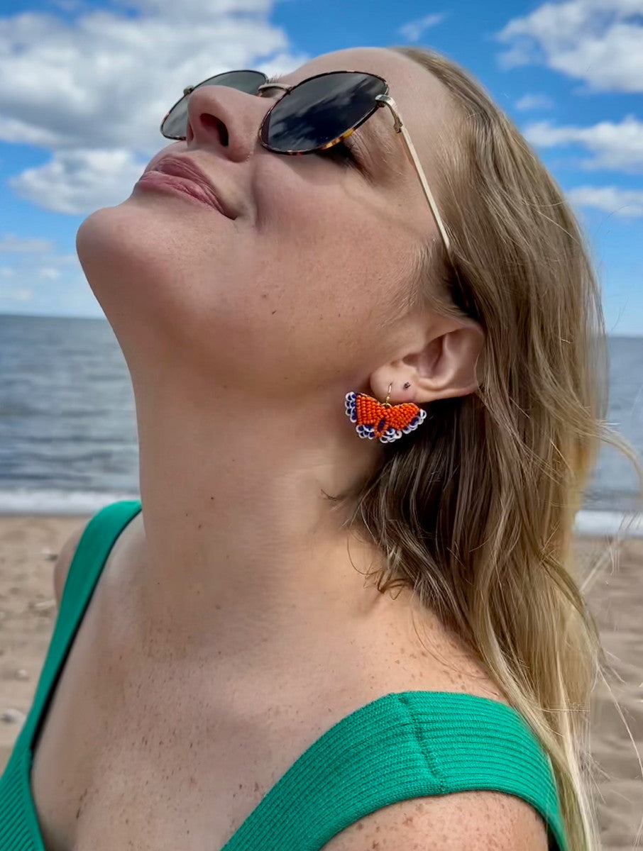 Woman wearing Fair Anita hand beaded butterfly earrings in peach and teal