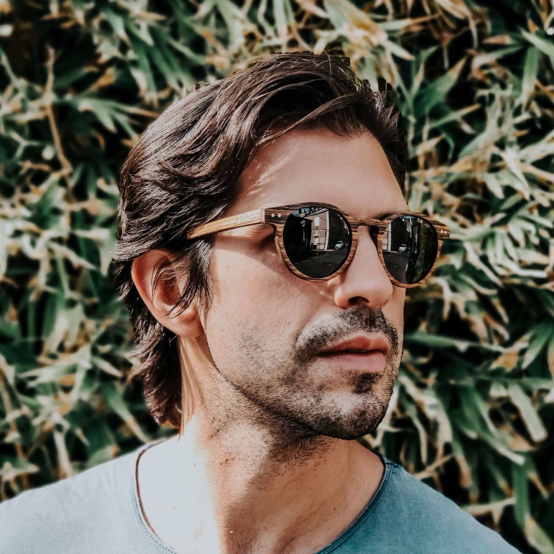 Man wearing sunglasses with a green leafy background