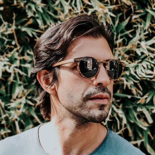 Man wearing sunglasses with a green leafy background