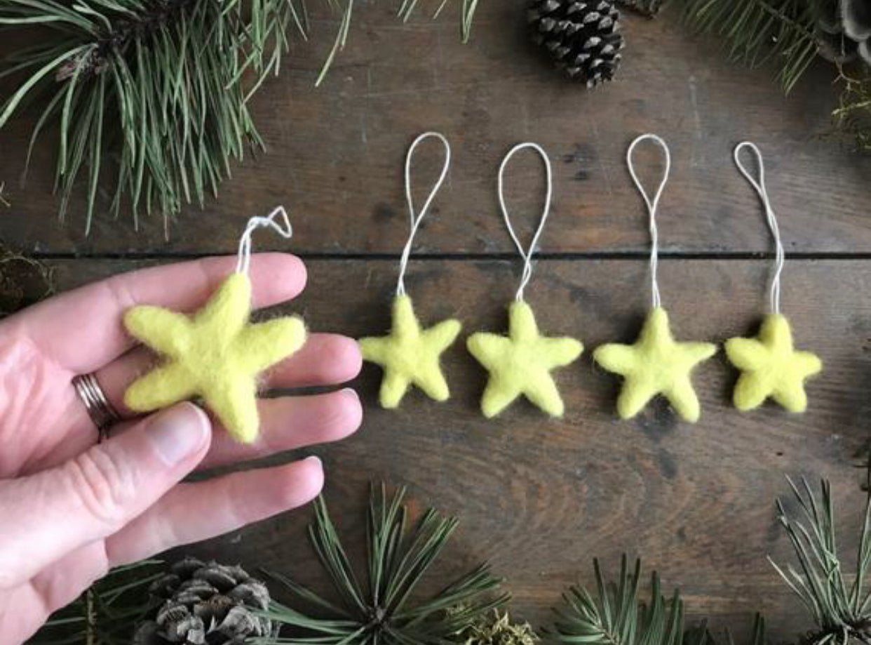 Mahonia Yellow wool star ornaments with cotton string loops, close-up view
