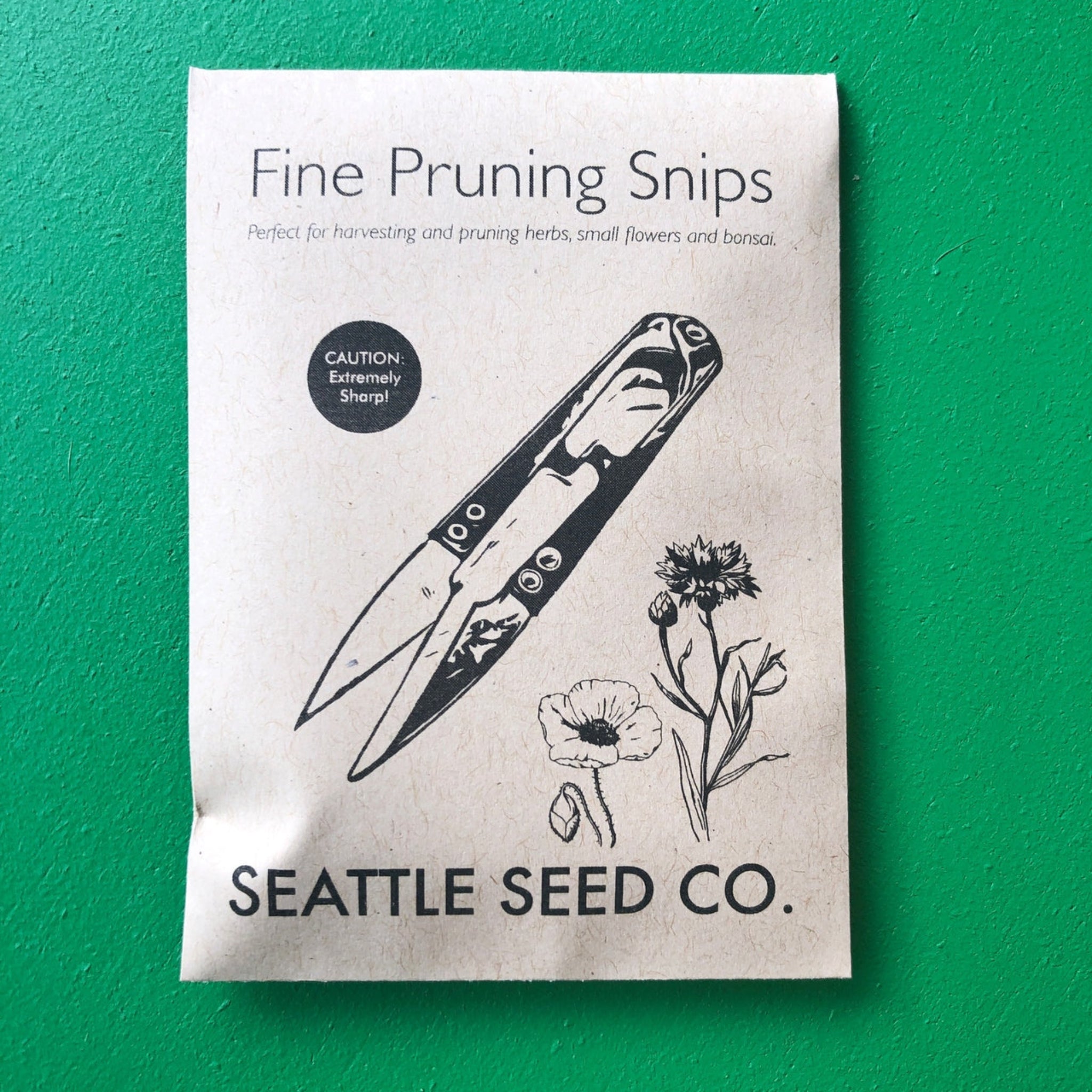 Package of 'Fine Pruning Snips' from Seattle Seed Co. on a green background