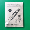 Package of 'Fine Pruning Snips' from Seattle Seed Co. on a green background