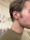 Model wearing faceted teardrop stud earrings in blue zircon stone, nickel-free recycled metal